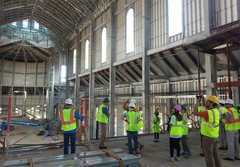 group of architects in safety vests and hardhats looking at a cathedral under construction